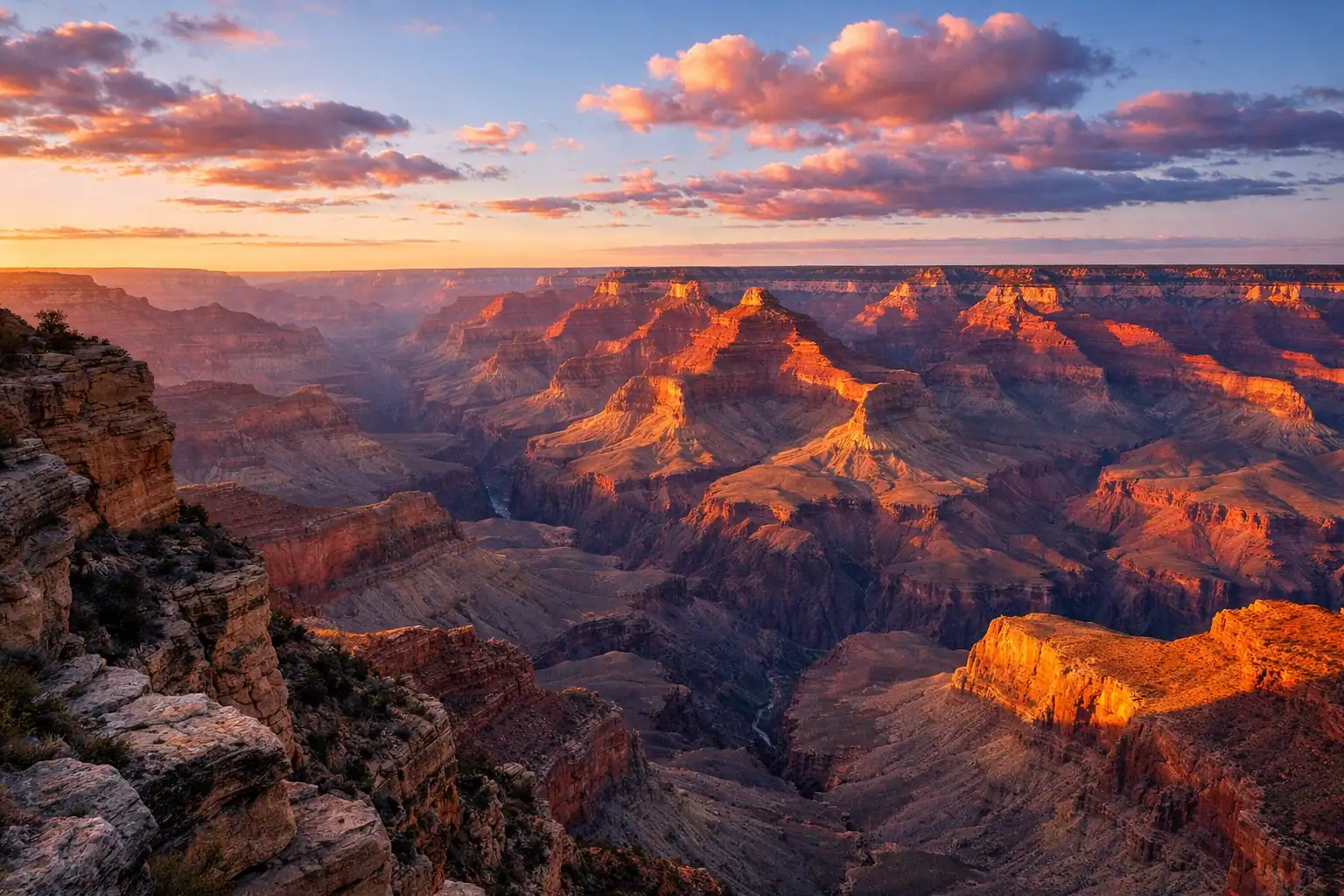 Zonsopgang bij de Grand Canyon South Rim met gouden lichtstralen op rode rotsformaties en paarse schaduwen