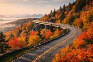 Blue Ridge Parkway tijdens herfstkleuren met kronkelende weg door rood-goud bos, Linn Cove Viaduct en mistige berglagen